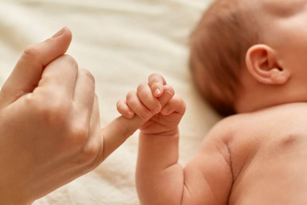 Faceless Mother With Naked Baby Infant Holding Mommy S Finger Mum Spending Time With Her Tiny Child On Light Background Scaled 1