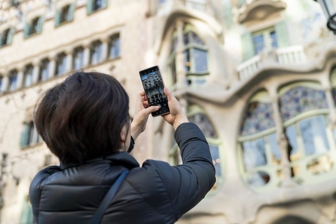 Una turista realiza una fotografía con su teléfono móvil a la Casa Batlló de Barcelona